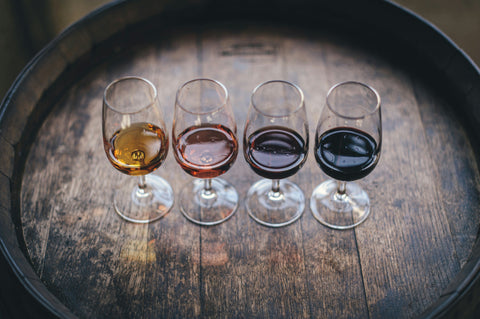 Four wine glasses containing different colours and styles of wine