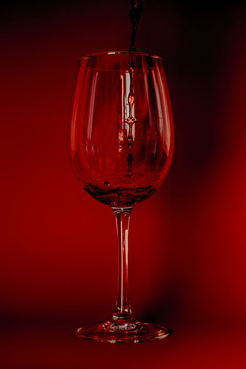 A vibrant glass of red wine being poured that looks exciting and different. 