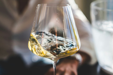 A glass of Torrontes white wine being swirled to release its tropical and floral aromas.